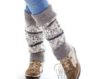 May include: Gray and white knitted leg warmers with a geometric pattern. The leg warmers are worn over blue jeans and brown boots.