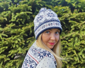 May include: A white and navy blue knit hat and sweater set with a snowflake pattern. The hat has a navy blue brim and a matching pattern. The sweater features a similar design with red accents. The set is perfect for winter.