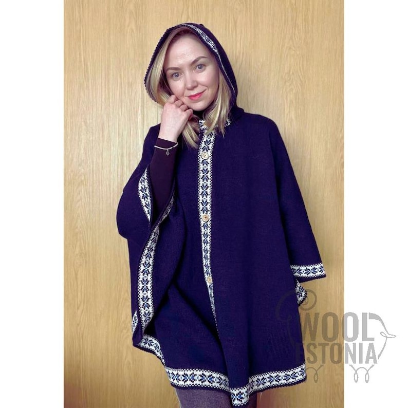 May include: A dark blue hooded cape with white and black trim. The cape has a button closure and is made of wool.