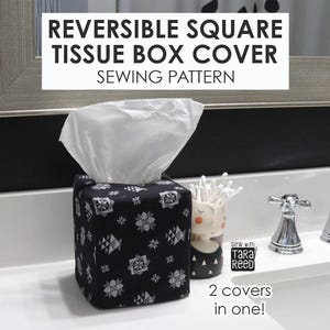 May include: A black fabric square tissue box cover featuring a white geometric star pattern. The text REVERSIBLE SQUARE TISSUE BOX COVER SEWING PATTERN is displayed at the top, with the text 2 covers in one! and Sew with TARA REED visible.