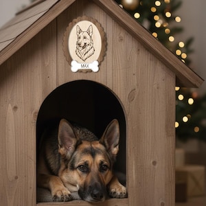 May include: A wooden dog house with a German Shepherd inside. The house has a decorative plaque with a dog portrait and the name "MAX". The dog is brown and black, lying down inside the house. A Christmas tree is in the background.