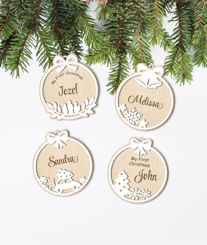 May include: Four wooden Christmas baubles with personalised names. Each bauble features a different design, including a wreath, a snowflake, a car with a Christmas tree, and a Christmas tree with snowflakes. The baubles are all white with brown text.