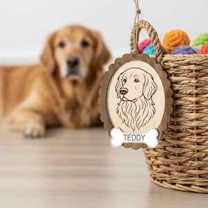 May include: Wooden dog ornament featuring a Golden Retriever illustration. The ornament has a scalloped edge and a bone-shaped tag that reads "TEDDY". A woven basket filled with colorful balls is in the background.