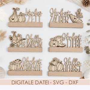 May include: Six laser-cut wooden signs featuring autumn-themed designs and text. The signs include illustrations of pumpkins, a wheelbarrow, an umbrella, rain boots, and mushrooms, with German and English phrases like Kürbis ZEIT and Hallo PUMPKIN.