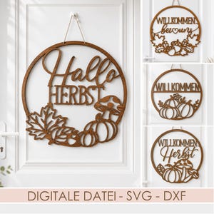Op de afbeelding: Een ronde wandhanger van bruin hout met de lasergesneden tekst Hallo HERBST en herfstmotieven zoals een paddenstoel, pompoenen en esdoornbladeren. Het ontwerp is voorzien van een dun touwtje om het object op te hangen.