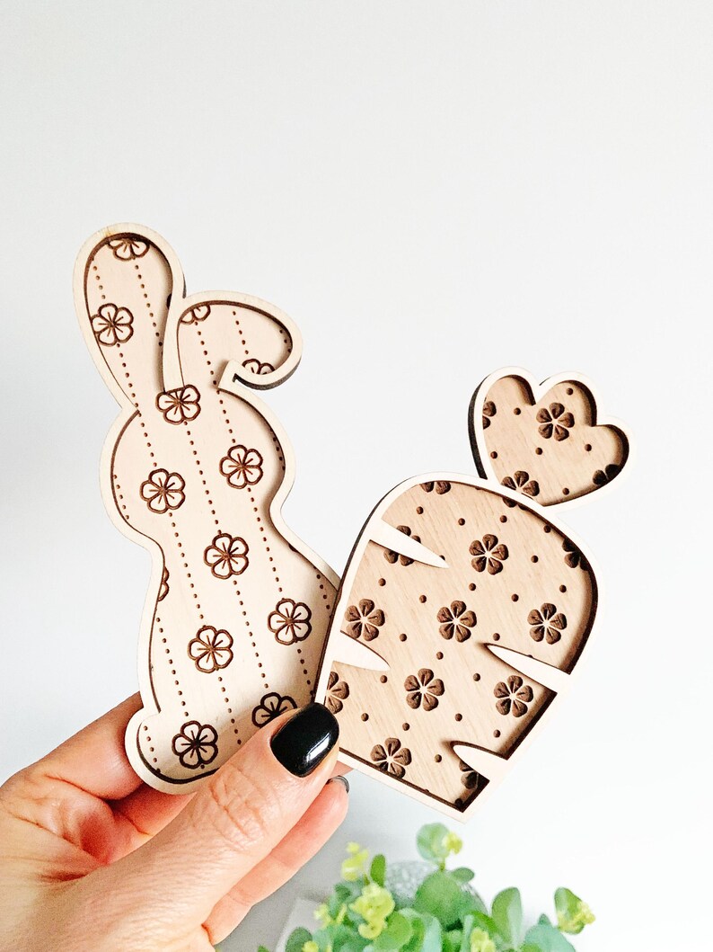 May include: Two wooden cutouts, a bunny and a carrot, both with a floral pattern. The bunny is brown and the carrot is orange.