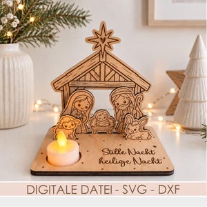 May include: A light-colored wooden nativity scene featuring a stable, a star, and figures of Mary, Joseph, and the infant Jesus, along with a lamb and a donkey. The base includes a circular cutout for a tea light and the text Stille Nacht heilige Nacht.