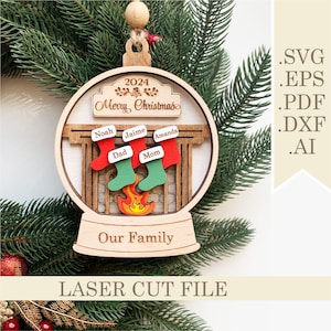 Puede incluir: Un adorno navideño de madera con forma de bola de nieve con una escena de chimenea en su interior. El adorno está decorado con el texto "2024 Feliz Navidad" y "Nuestra familia". Hay cuatro calcetines colgados de la chimenea, cada uno con un nombre escrito: Noah, Jaime, Amanda y Mamá. El adorno está cortado con láser y viene en los formatos de archivo SVG, EPS, PDF, DXF y AI.