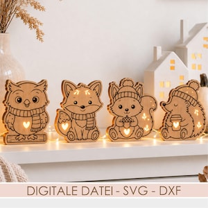 May include: Four light-up wooden animal figures including an owl on a branch, a fox, a squirrel holding an acorn, and a hedgehog holding a cup. Each figure features cut-out heart and leaf shapes that glow with warm light. Text reads: DIGITALE DATEI - SVG - DXF.