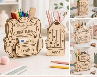 Può includere: Un organizer da scrivania in legno a forma di zaino con il testo Alles Gute zur EINSCHULUNG e Louise, accanto a un portapenne a forma di matita con il nome Anna. Il set include varie matite colorate e un righello all'interno degli scomparti.