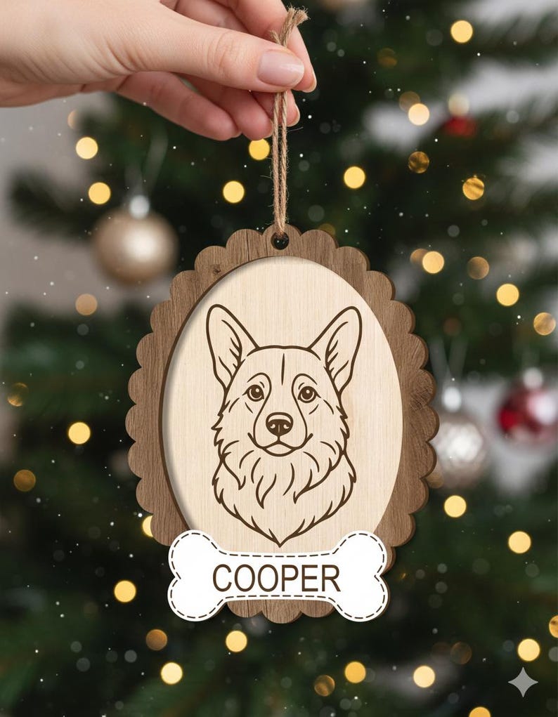 May include: Wooden Christmas ornament featuring a corgi dog portrait. The ornament has a light wood oval center with a detailed dog illustration, framed by a darker wood scalloped edge. A bone-shaped tag at the bottom reads "COOPER".