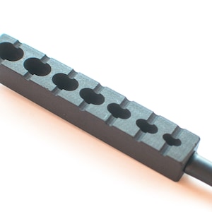May include: A black metal tool with six round holes, used for shaping or sizing objects.