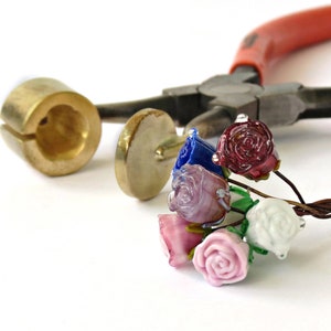 May include: A bunch of glass roses in various colours, including pink, white, blue, and red, are attached to wire stems. The roses are arranged in a bunch and are ready to be used in a craft project.
