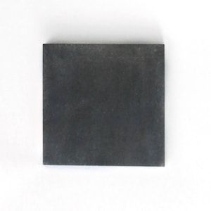 Puede incluir: Un azulejo cuadrado negro sólido con una superficie ligeramente texturizada.