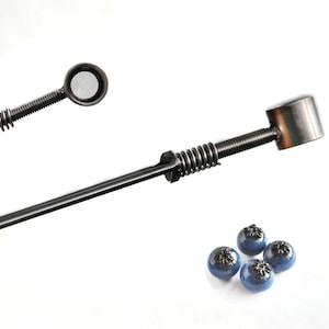 May include: Two metal tools with a spring mechanism and a mesh strainer. Four blueberries are in the lower right corner of the image.