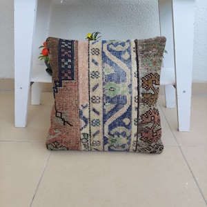 May include: A decorative pillow with a patchwork design featuring various shades of brown, blue, and beige. The pillow is made from a woven fabric with intricate patterns and is perfect for adding a touch of bohemian style to any room.