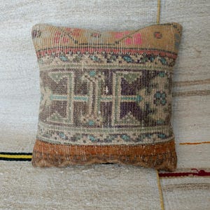 May include: A decorative pillow with a vintage, hand-woven design. The pillow features a geometric pattern in shades of brown, beige, and blue. The pillow is made of a soft, textured fabric.