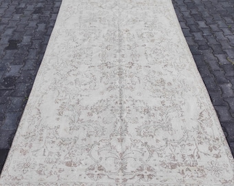 May include: A vintage cream-colored rug with a delicate floral pattern in a light brown color. The rug has a distressed look and a subtle sheen.