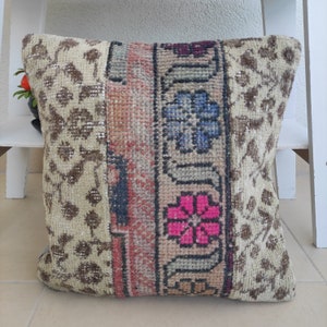 Puede incluir: Una almohada decorativa con un diseño de patchwork que presenta un fondo beige con patrones florales marrones, un patrón floral rosa y azul y un patrón geométrico rojo y marrón.