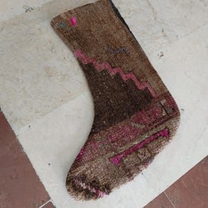 May include: A brown and pink patterned stocking made from woven fabric. The stocking has a geometric design with pink and brown zigzags and a pink and brown stripe.