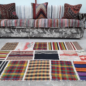 May include: A colorful patchwork rug with a variety of patterns and colors, including red, blue, yellow, and green. The rug is made of woven fabric and has a fringed edge.
