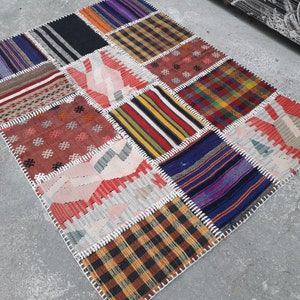 Può includere: Un tappeto patchwork colorato fatto di diversi tessuti e motivi. Il tappeto è rettangolare e ha un bordo bianco. Il tappeto è composto da diversi colori, tra cui rosso, blu, verde, giallo e marrone.