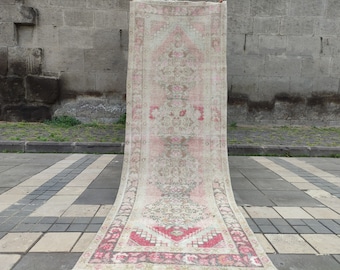 May include: A vintage pink and cream runner rug with a floral pattern. The rug is hand-woven and has a distressed look.