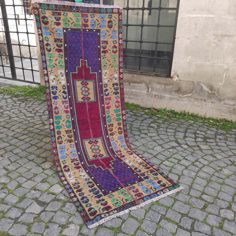 May include: A vintage Turkish rug with a colorful geometric pattern in shades of red, blue, yellow, and green. The rug has a fringe border and is made of wool.