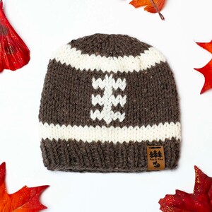 May include: Brown knit beanie with a white football design and a brown leather tag that says "Fox & Pine".