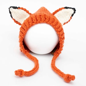 May include: Orange knitted fox hat with black and white ears and long ties.