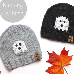 May include: Two knitted hats with a ghost design. The hats are grey and black with white ghost faces. The hats have a brown leather tag with the text "Fur & Pine" on them.