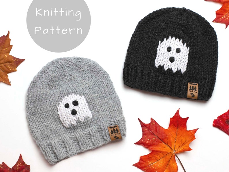 May include: Two knitted hats with a ghost design. The hats are grey and black with white ghost faces. The hats have a brown leather tag with the text "Fur & Pine" on them.