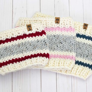 May include: Three knitted headbands in different color combinations. The headbands are white with stripes of burgundy, pink, and navy blue. Each headband has a small brown leather tag with the text "Pine & Pine" on it.