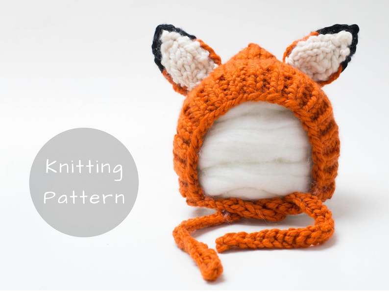 Op de afbeelding: Breipatroon voor een vossenmuts. De muts is oranje met zwarte en witte vossenoren. De muts heeft een strik onder de kin.