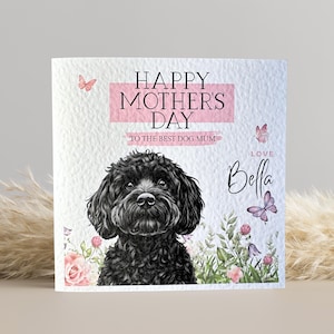 May include: Mother's Day card with a black dog illustration. The card reads "HAPPY MOTHER'S DAY" in pink, with "TO THE BEST DOG MUM" below. Butterflies and floral details surround the dog, with the name "Bella" written in cursive.