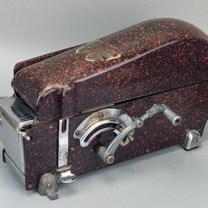 May include: A vintage red and black speckled metal envelope sealer with a silver butterfly design and a crank handle.