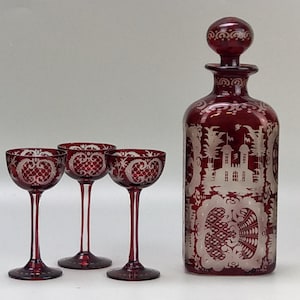 Könnte beinhalten: Set aus vier rubinroten Glaskaraffen und Schnapsgläsern mit geätzten weißen Blumen- und Schlossmotiven.