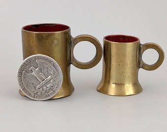 A couple of brass ring shots measures with red enamel