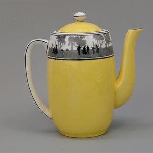 May include: A yellow ceramic coffee pot with a lid and a curved spout. The top of the pot features a black and white decorative band with silhouettes of people and trees. The handle and spout are cream-colored.