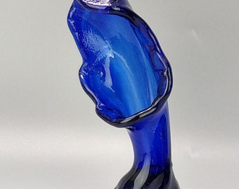 May include: A cobalt blue glass vase with a unique, organic shape. The vase has a wide opening and a narrow base.