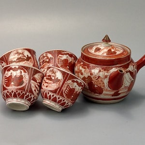 Könnte beinhalten: Ein rotes und weißes japanisches Teeset mit einer Teekanne und vier Tassen. Das Set ist mit einem traditionellen japanischen Design verziert.
