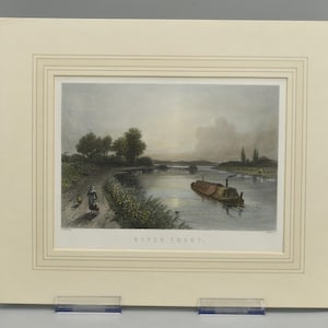 May include: A matted print titled RIVER TRENT featuring a landscape scene with a narrow boat on a calm river, a dirt path with a figure walking along the bank, green trees, and a soft, hazy sky. The artwork is framed in a cream-colored mat board.