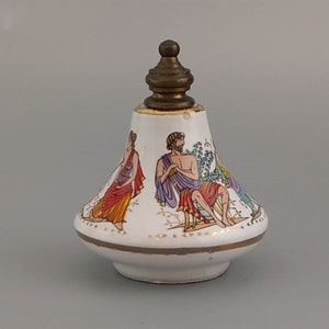 Può includere: Una bottiglia di ceramica bianca con un bordo dorato e un tappo in ottone. La bottiglia è decorata con una scena colorata di persone in abiti classici.
