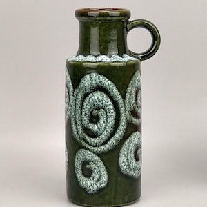 Peut inclure: Un vase en céramique vert foncé avec une anse, orné de spirales blanches et vertes. Le bord et la poignée sont brun foncé. Ce vase décoratif convient à la décoration intérieure.