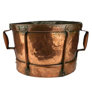 May include: A copper planter with two handles and a hammered finish. The planter has a rounded shape and is made of solid copper.