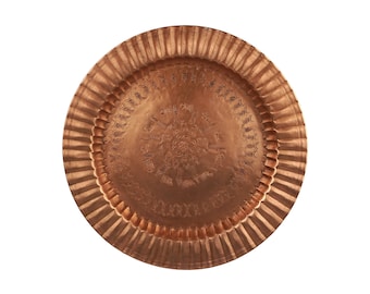 May include: A round copper tray with a decorative embossed design. The tray has a fluted edge and a hammered finish.