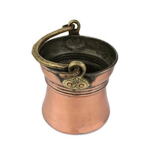 Könnte beinhalten: Ein kleiner Kupfer-Eimer mit einem Messinggriff und dekorativen Akzenten. Der Eimer ist etwa 15 cm hoch und hat einen Durchmesser von etwa 10 cm.