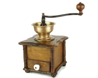 May include: Antique wooden coffee grinder with a brass hopper and a hand crank. The grinder has a drawer for storing coffee beans.