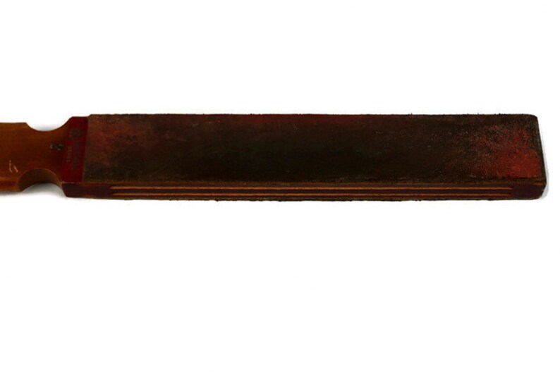 May include: A wooden and leather strop for sharpening straight razors. The strop has a wooden handle and a leather strap.