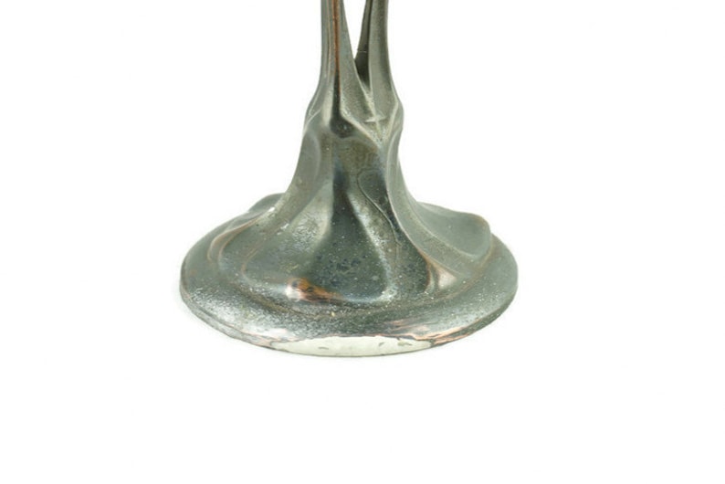 May include: A silver metal base with a swirling, organic design. The base is smooth and has a slight sheen.